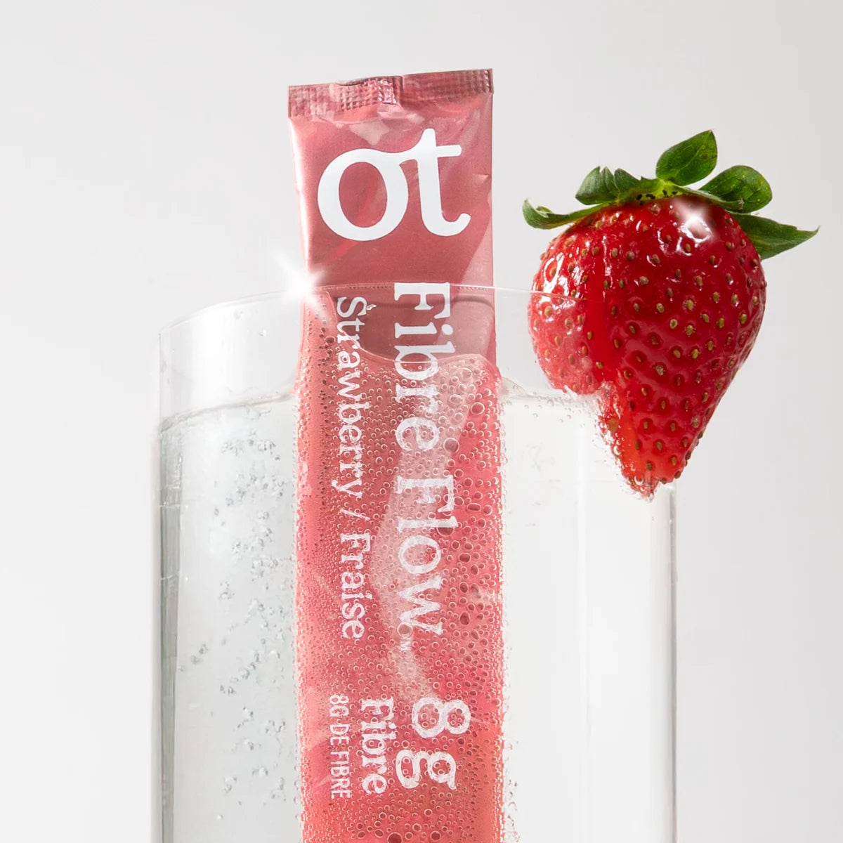 A portable Fiber Flow Strawberry drink stick beside a glass